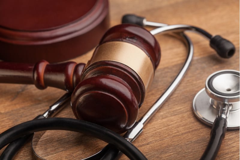 Close up of brown gavel and stethoscope on wooden table