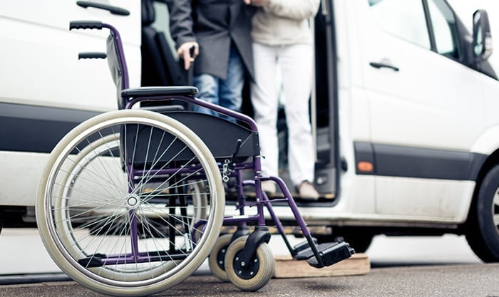 Nurse helping disabled person exit van to get to wheelchair