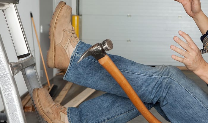 Worker falls off of a ladder in a garage and drops a hammer.